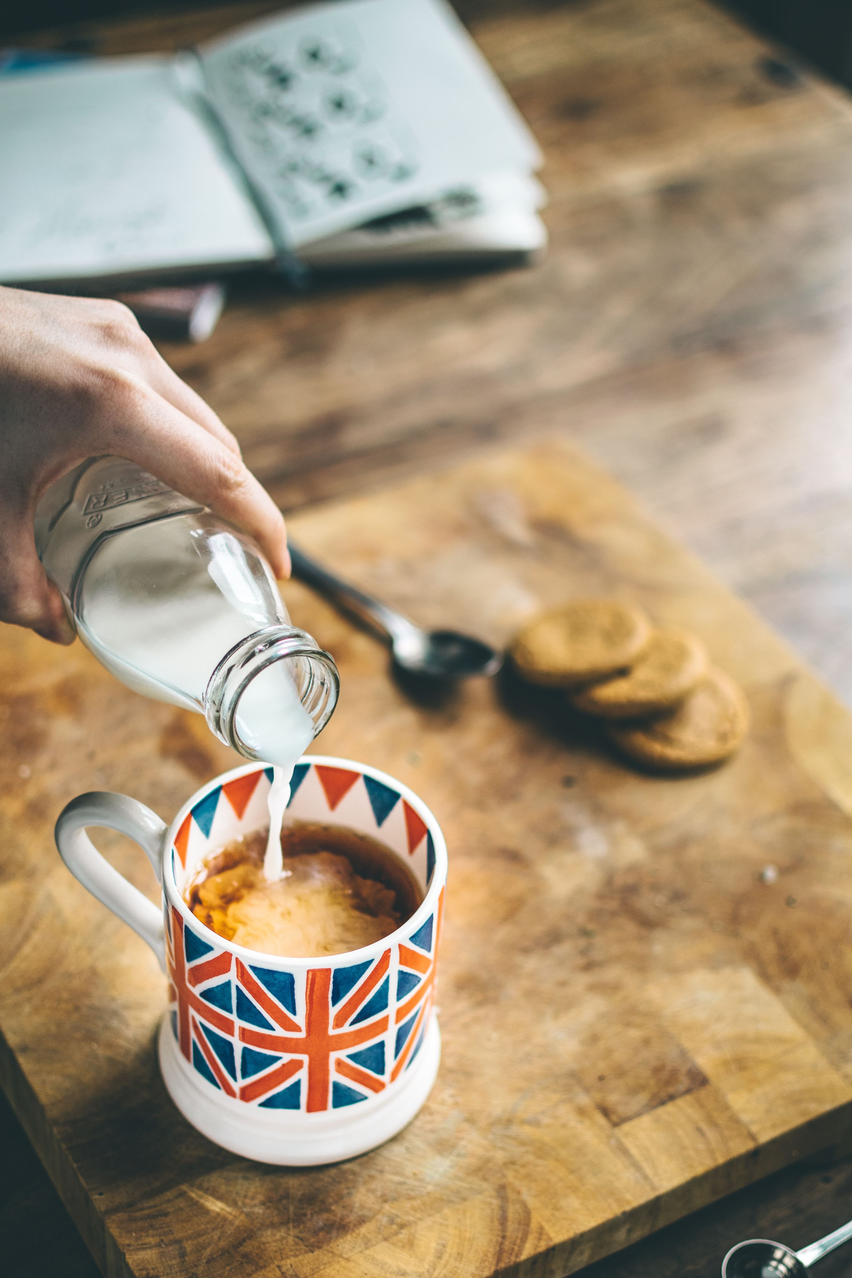 Milk being poured into a teacup with a design of the British flag on the cup